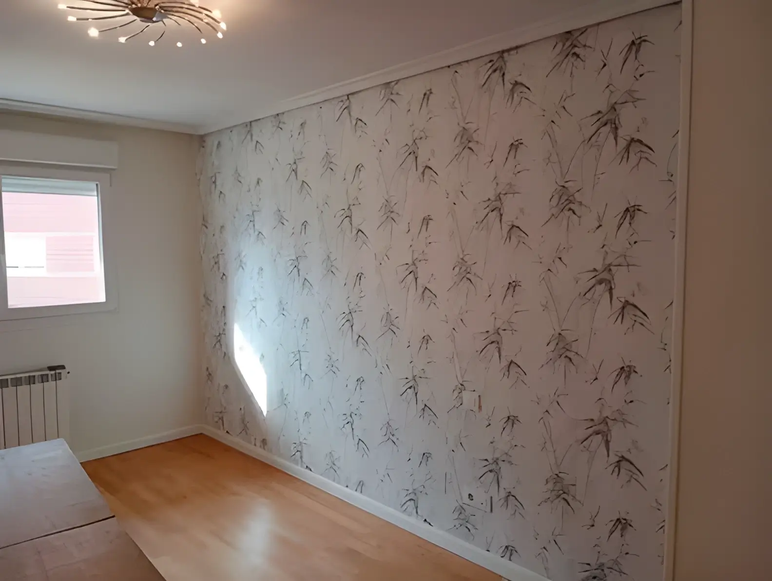 Los Pintores Getafe colocando papel pintado en pared de acento de habitación luminosa