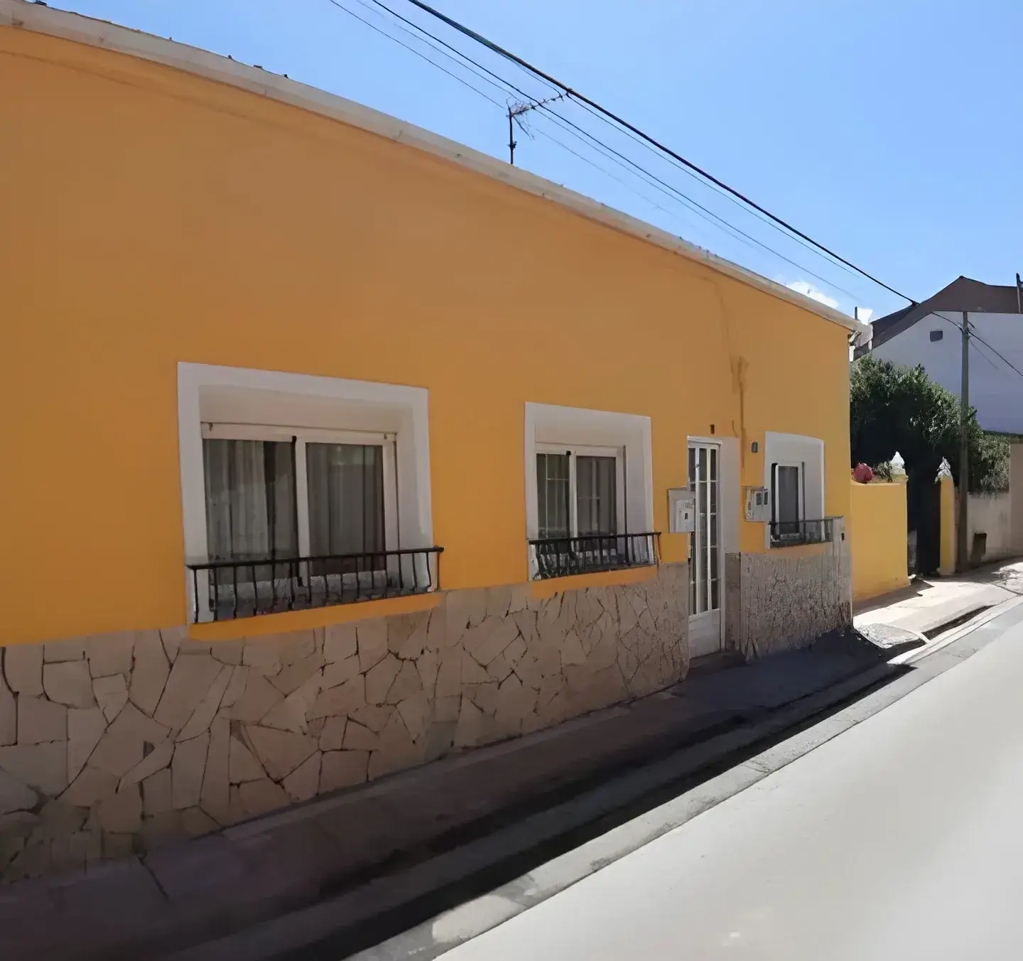 Los Pintores Getafe Fachada de casa tradicional pintada en color amarillo con zócalo de piedra